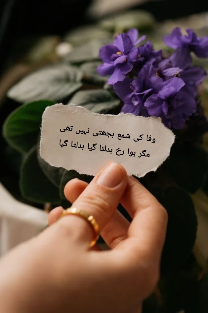 urdu poetry wafa ki shama hand holding torn paper note with purple flowers nearby